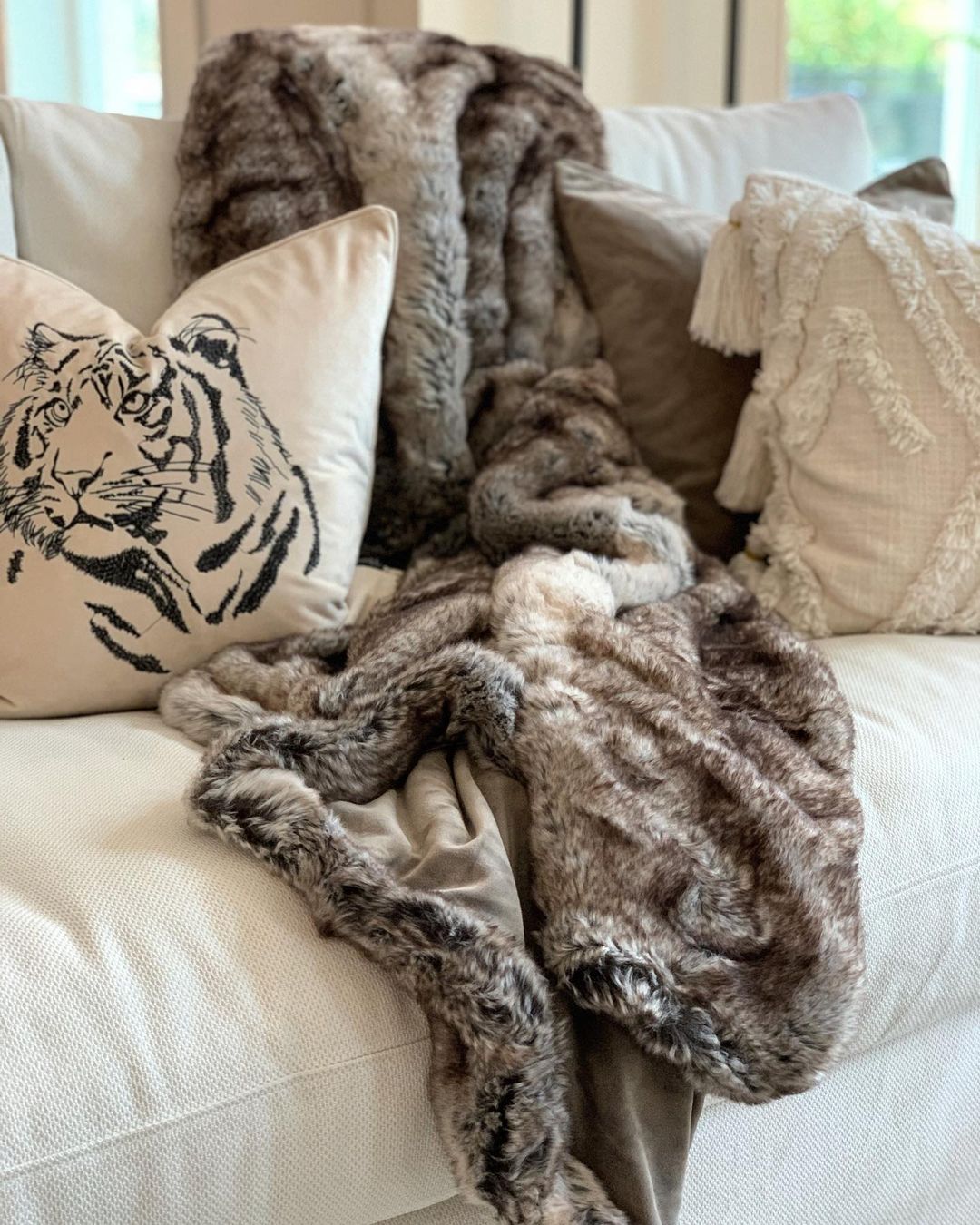 beige prydnadkudde i sandfärg liggandes i en vit soffa